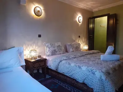 a bedroom with two beds and two lamps on the wall at Riad Simon in Marrakech