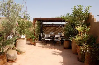 a patio with potted plants and a table and chairs at Riad Massiba in Marrakech