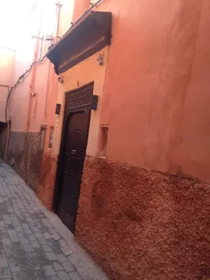 an alley with a black door in a building at Riad JEREMY in Marrakech