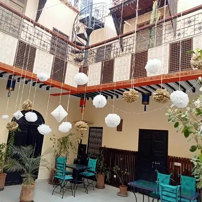 a restaurant with blue chairs and white pendant lights at Riad JEREMY in Marrakech
