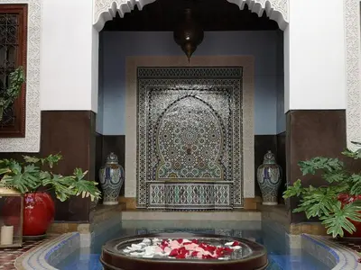 a room with a large rug and a fountain in front of a wall at Riad Charme d'Orient Adults Only in Marrakech
