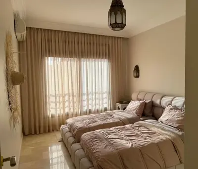a bedroom with two beds and a large window at Caprice Palace in Marrakech