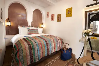 a bedroom with a bed with a colorful blanket at Riad Dar Amanza en exclusivité avec 4 chambres au coeur de la médina in Marrakech