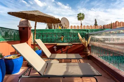 a patio with chairs and an umbrella on a roof at Riad Bianca Marrakech in Marrakech