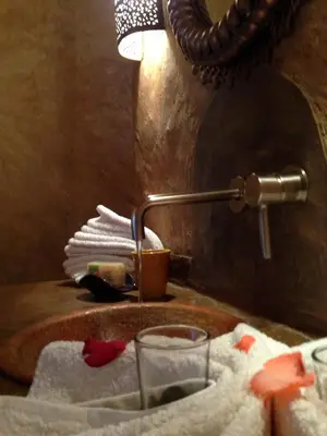 a bathroom sink with a faucet and a glass of water at Riad Mehdia & spa in Marrakech