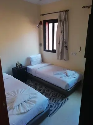 two beds in a room with a window at LINA APPARTEMENT in Marrakech