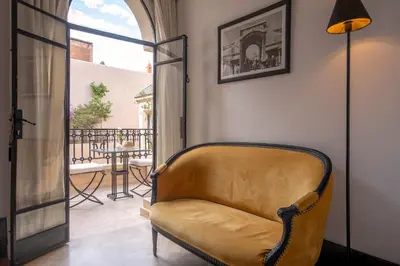 a yellow couch in a room with a balcony at Riad & Spa Azzouz in Marrakech