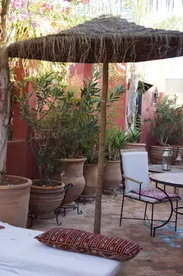 a patio with tables and chairs and potted plants at Riad Honey in Marrakech