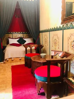 a bedroom with a bed and a red rug at Riad Hotel Sherazade in Marrakech
