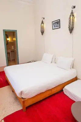 a large white bed in a room with a red rug at Riad Dar Aicha en Exclusivité in Marrakech