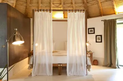 a bedroom with a bed with curtains in it at Hotel Les Cinq Djellabas in Douar Caïd Layadi