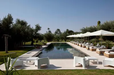 a swimming pool with white lounge chairs and umbrellas at Hotel Les Cinq Djellabas in Douar Caïd Layadi