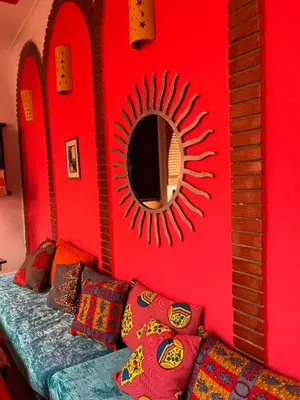 a red wall with a mirror and a couch with pillows at Riad N10 in Marrakech