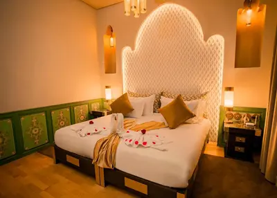 a bedroom with a large bed with a white headboard at Palais Dar Si Aissa ALL-SUITES in Marrakech