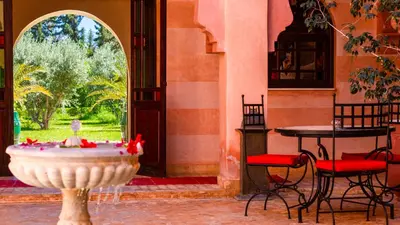 a fountain in a room with a table and chairs at L'OLIVERAIE DE L'ATLAS in Marrakech
