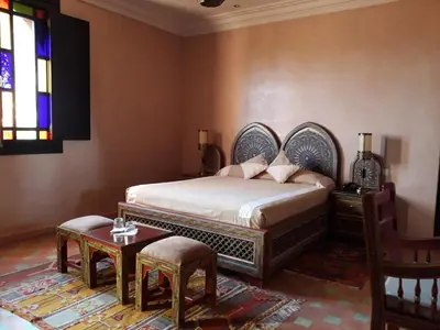 a bedroom with a bed and a table and a window at L'OLIVERAIE DE L'ATLAS in Marrakech