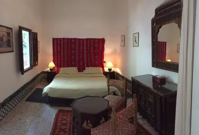 a bedroom with a bed and a mirror and chairs at Riad Dar El Assafir in Marrakech
