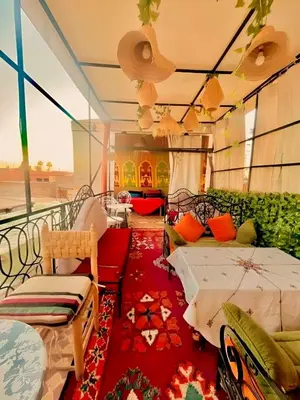 a room with a balcony with two beds and a rug at Riad Lalla Marrakech in Marrakech