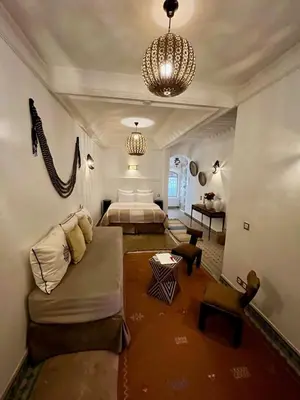 a bedroom with a bed and a couch and a chandelier at Riad Ecila in Marrakech