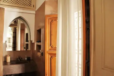 a bathroom with a sink and a door with a mirror at Riad Miski in Marrakech