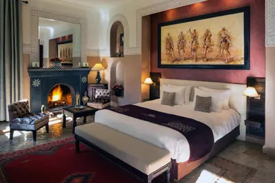 a bedroom with a large bed and a fireplace at Riad Monceau in Marrakech