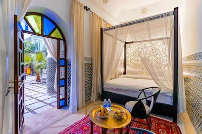 a bedroom with a bed and a table and a window at Riad Dar Dialkoum in Marrakech