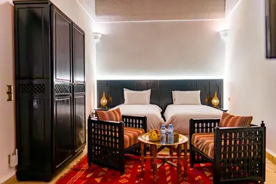 a bedroom with two beds and a table and chairs at Riad Dar Dialkoum in Marrakech