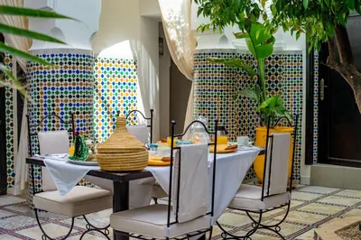 a dining room with a table and chairs and tiles at Riad Dar Dialkoum in Marrakech