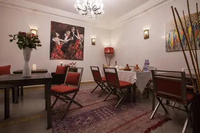 a dining room with a table and chairs and a painting at Riad Shanima SPA Marrakech in Marrakech