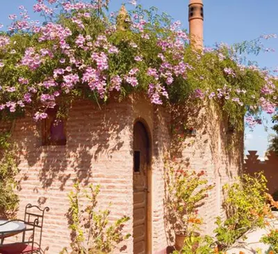 a brick building with pink flowers on it at Dar Attajmil in Marrakech