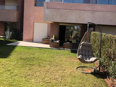 a swing in a yard in front of a building at Appartement à Prestigia Marrakeche avec jardin in Marrakech