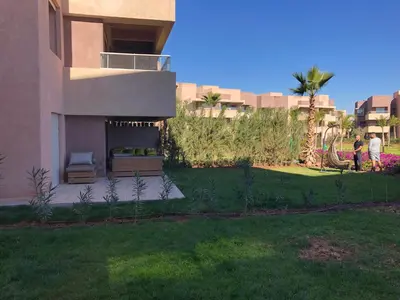 two people standing in a yard next to a house at Appartement à Prestigia Marrakeche avec jardin in Marrakech