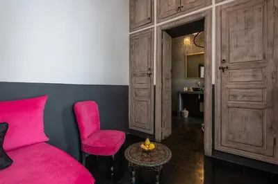 a bedroom with a pink bed and a chair and a table at Riad la Parenthèse by Sashema in Marrakech