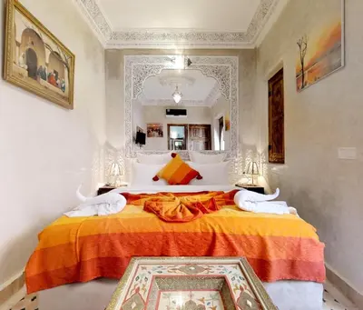 a bedroom with a large bed with an orange blanket at Riad Sania By Ghali in Marrakech