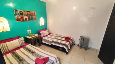 a room with two beds and a table in it at Riad Abdou in Marrakech