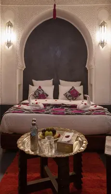 a bed with a table with a tray of fruit on it at Riad Alaka in Marrakech