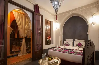 a bedroom with a bed and a table and a chandelier at Riad Alaka in Marrakech