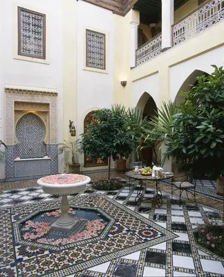 a courtyard with a table and a fountain in a building at Riyad Al Moussika in Marrakech