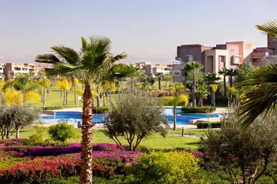 a palm tree in the middle of a park with flowers at Darkech Prestigia Luxury Apt in Marrakech