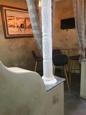 a white column in a room with chairs and a painting at Riad Le Marrakech Berrima in Marrakech