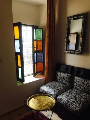 a living room with a chair and a table and a mirror at Ryad Bianco in Marrakech