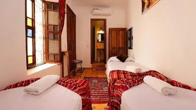 a room with three beds and a couch in it at Ryad Bianco in Marrakech