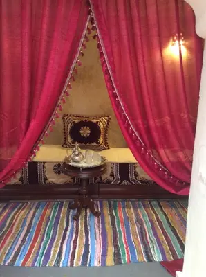 a room with red curtains and a small table with a table at Ryad Bianco in Marrakech