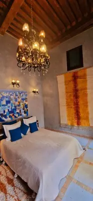 a bedroom with a large bed and a chandelier at Riad de Vincent in Marrakech