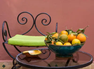 a bowl of fruit on a table with a bench at Riad Wardate Rita in Marrakech