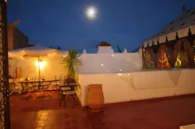 a white building with a table and umbrella at night at Riad Morgane in Marrakech
