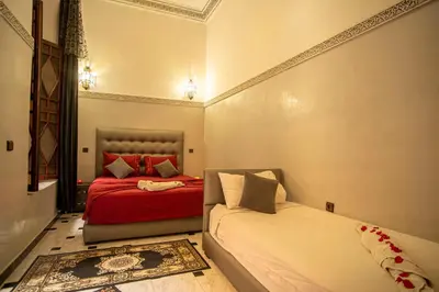 a bedroom with two beds with red and white pillows at Riad Aymane in Marrakech