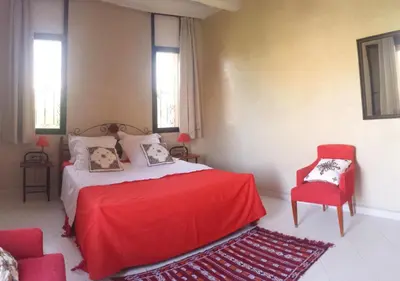 a bedroom with a red bed and a red chair at Villa clos Odette in Marrakech
