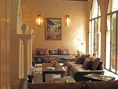 a living room with couches and tables and windows at Riad Le Perroquet Bleu Suites & Spa in Marrakech