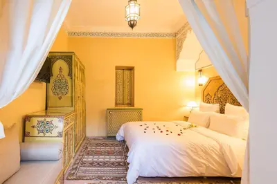 a bedroom with a white bed and yellow walls at Riad Tahyra in Marrakech
